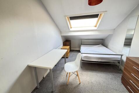 A cozy student bedroom featuring a bed and a sm...