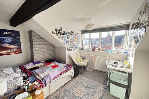 A cozy bedroom featuring a single bed, a desk, ...