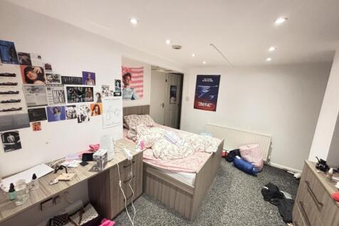 A cozy bedroom with a neat bed covered in a col...