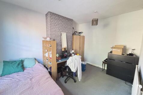 A cozy single bedroom featuring a bed with colo...