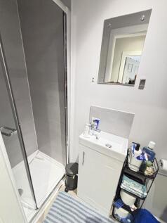 A compact bathroom featuring a shower enclosure...