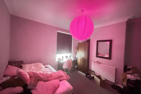 A cozy double bedroom with soft pink walls illu...