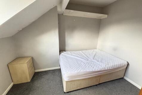 A cozy single bedroom with a sloped ceiling, a ...