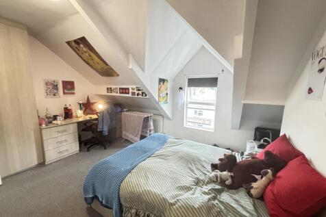 A cozy attic bedroom featuring a neatly made be...