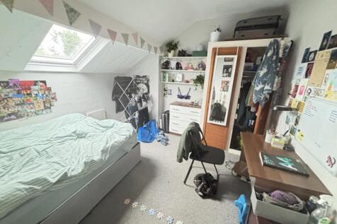 A cozy bedroom with a single bed, a desk, and p...