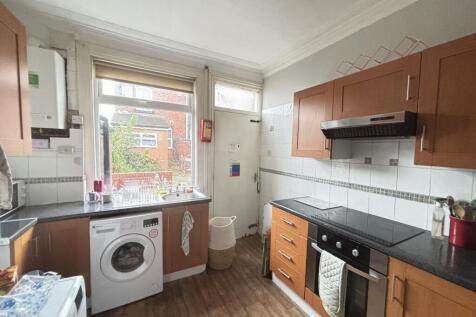 A well-lit kitchen featuring a washing machine,...