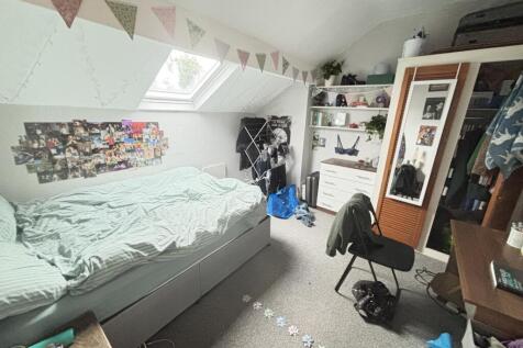 A cozy bedroom with a single bed, cluttered wit...