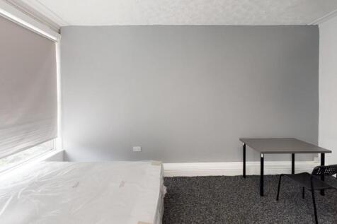 A tidy bedroom with neutral walls, featuring a ...