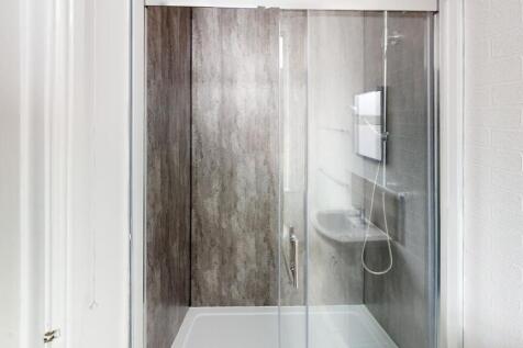 A clean and modern shower room featuring a glas...
