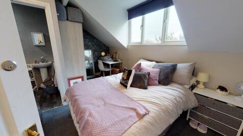 A well-lit double bedroom with a comfortable be...