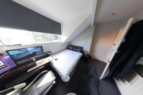 A cozy single bedroom featuring a bed with stor...