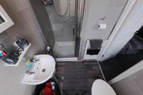 A modern bathroom with a shower, clean tiled wa...