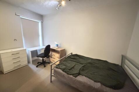 A neat and cozy bedroom featuring a bed with si...