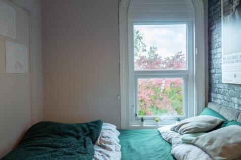 A well-lit double bedroom with a large window o...