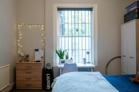 A bright and tidy bedroom featuring a large win...