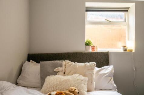 A cozy bedroom featuring a neatly made bed with...