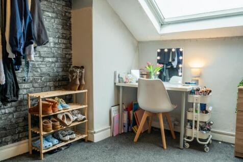 A well-lit bedroom featuring a white desk with ...