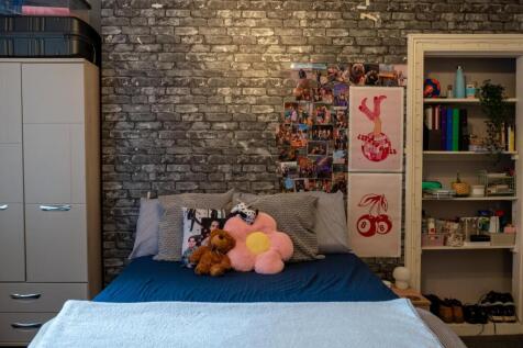 A cozy bedroom featuring a bed with plush toys,...