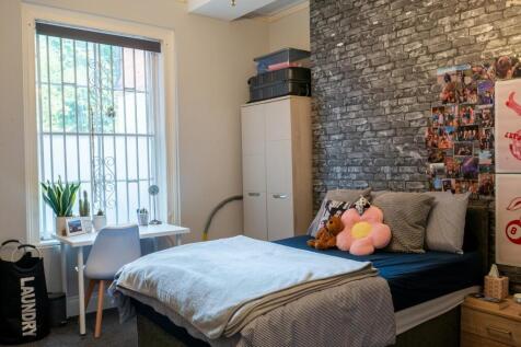 A cozy single bedroom with a neatly made bed, s...