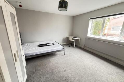 A bright and tidy bedroom with a comfortable si...