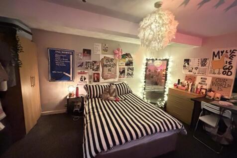 A cozy bedroom featuring a striped bedspread, p...