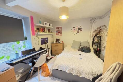 A cozy bedroom featuring a double bed, a desk w...