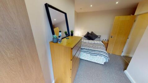 A cozy single bedroom featuring a bed, desk, an...