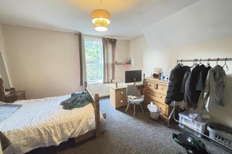 A cozy and well-lit bedroom featuring a bed, a ...