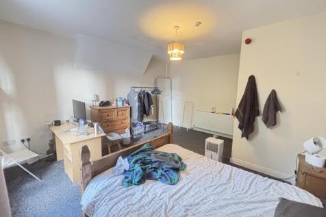 A cozy bedroom featuring a neatly made bed with...