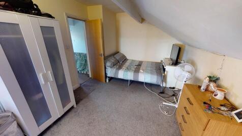 A cozy single bedroom featuring a single bed wi...