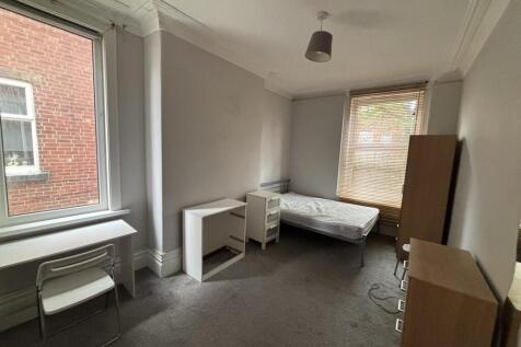 A modest bedroom with natural light coming from...