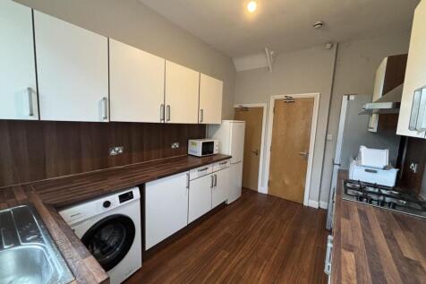A modern kitchen with white cabinetry, wooden f...