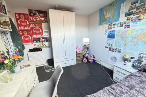 A well-organized student bedroom featuring a co...