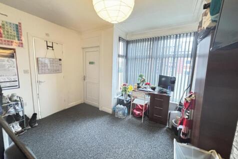 A tidy and well-lit room with a window allowing...