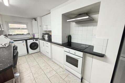 Bright galley-style kitchen with modern white c...