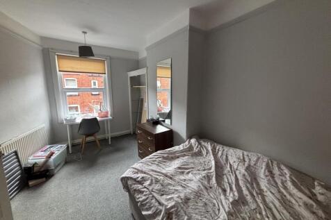 A cozy and well-lit single bedroom featuring a ...