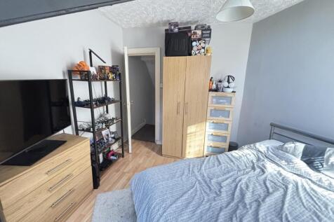 A bright and tidy bedroom featuring a comfortab...