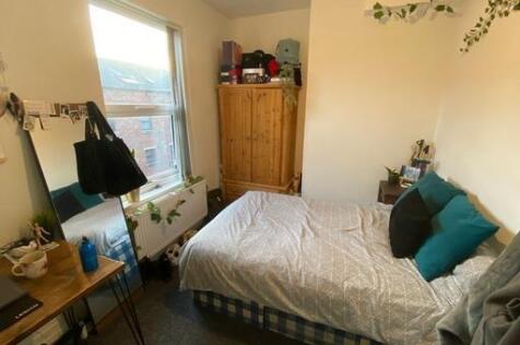 A cozy student bedroom featuring a neatly made ...