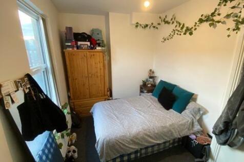 A cozy bedroom featuring a bed with pillows, a ...