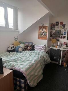 A cozy single bedroom featuring a well-made bed...