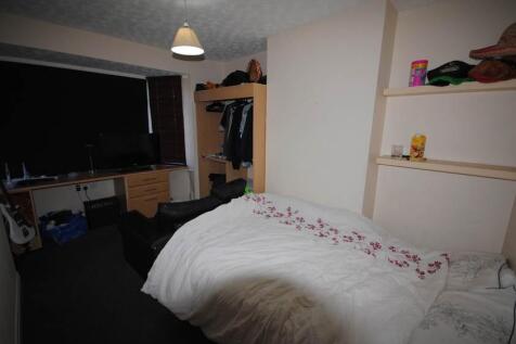 A bright and cozy bedroom featuring a neatly ma...