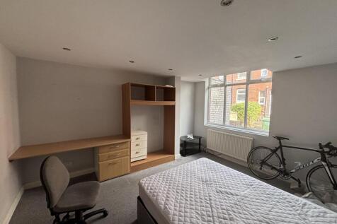 A bright and tidy student bedroom featuring a c...