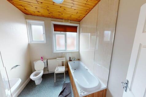 A bright and tidy bathroom featuring a bathtub,...