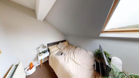 A cozy bedroom featuring a single bed placed un...