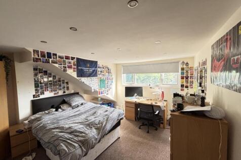 A well-lit, cozy bedroom featuring a comfortabl...