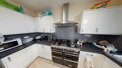 A modern, well-lit kitchen with white cabinets,...