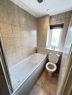 Bright and clean bathroom featuring a bathtub a...