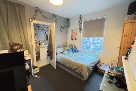 A cozy student bedroom featuring a double bed, ...