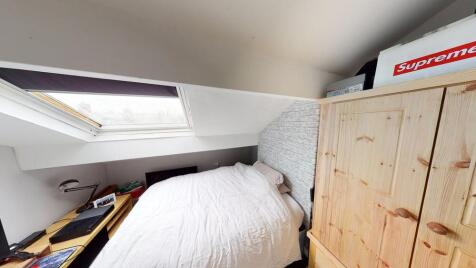 A cozy bedroom featuring a single bed with a pl...