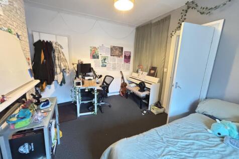 A cozy bedroom featuring a bed, desk, and wardr...